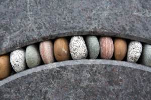 Foto: kleine bunte Steine in einem leichten Bogen stecken in einer Ausfräsung eines Granitblocks